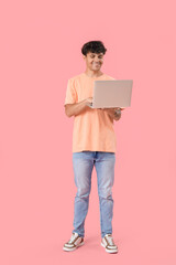 Male programmer working with computer on pink background
