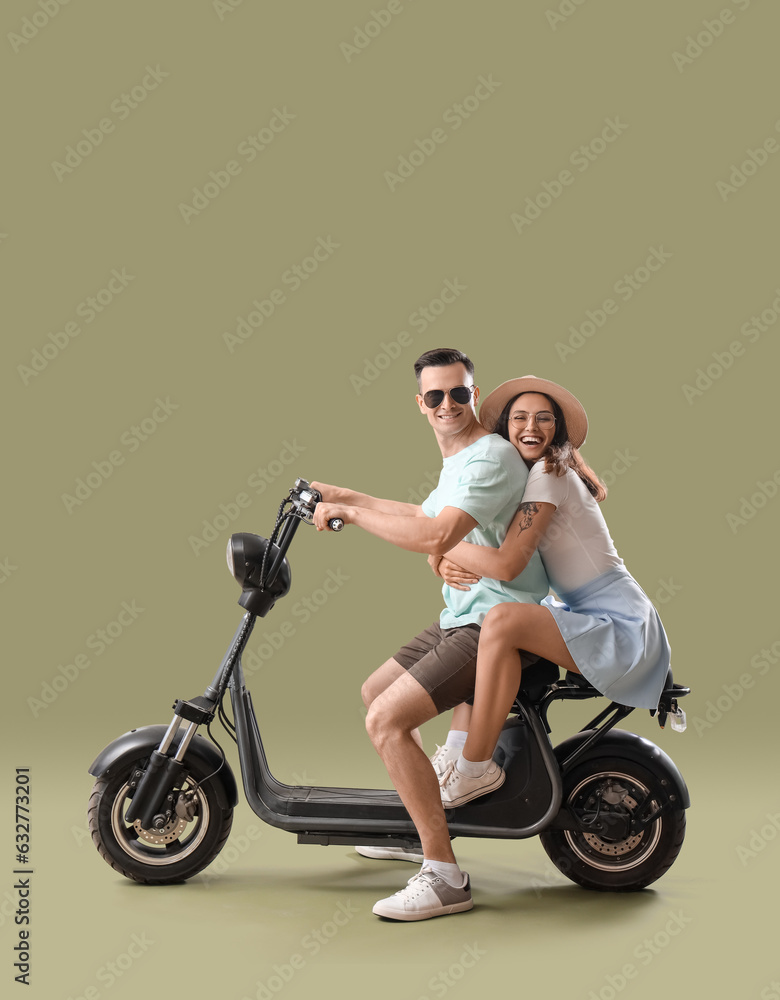 Wall mural Young couple with electric bike on green background