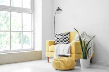 Yellow armchair with pillow and plaid in interior of living room