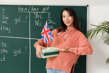 Female English teacher with UK flag and books in classroom