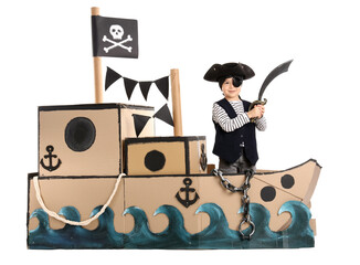 Cute little pirate playing with sword in cardboard ship on white background