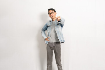 A confident man gives thumbs up with his left hand. Indonesian or southeast asian model isolated with white wall background.