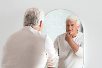 Fototapeta na wymiar Senior man looking in mirror at home