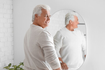 Obraz na płótnie Canvas Senior man looking in mirror at home