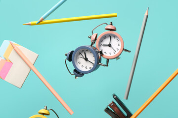 Different stationery and alarm clocks flying on color background