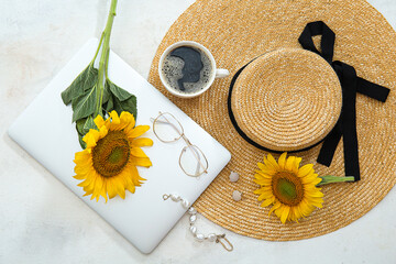 Beautiful sunflowers, accessories, cup of coffee and modern laptop on light background