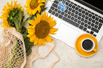 Eco bag with beautiful sunflowers, cup of coffee and modern laptop on light background