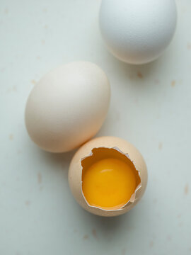 Close up, three chicken eggs on white, one cracked open