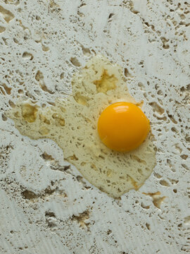 Broken, raw egg on stone