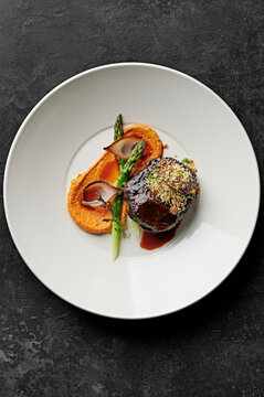 Slow-cooked beef cheek, charred shallots, asparagus spears, romesco, pancetta herb crumbs