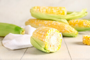 Fresh corn cobs on white tile table