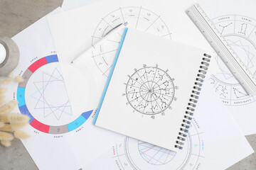 Zodiac wheels and natal chart for making astrological predictions on table, flat lay