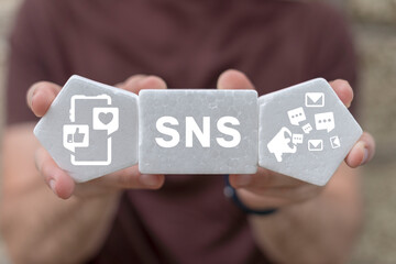 Man holding white plastic foam blocks with icons and sees acronym: SNS. Social Media. Concept of...