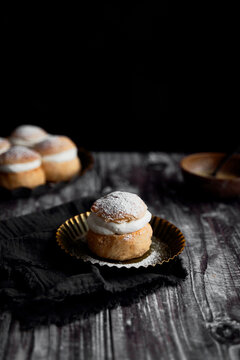 Semlor Buns on Wood Backdrop with icing sugar on tray