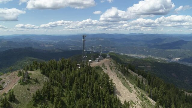 Aerial push forward on cell tower on mountain summit in northern Idaho near Kellogg
