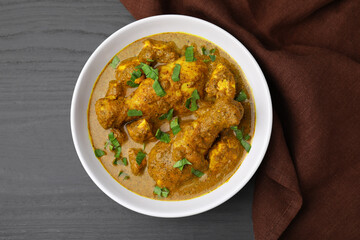 Delicious chicken with curry sauce on grey wooden table, top view