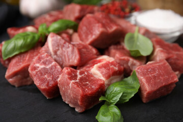 Cut fresh beef meat and basil leaves on slate plate, closeup