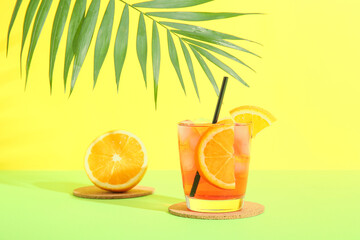 Glass of tasty Negroni cocktail and palm leaf on color background