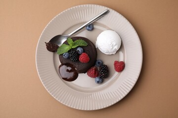 Delicious chocolate fondant served with fresh berries and ice cream on beige background, top view