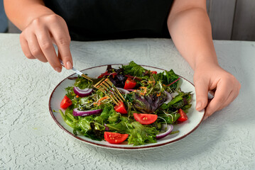 Woman eating fresh vegetable salad at table