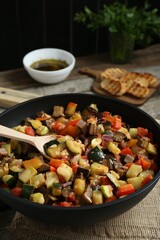 Delicious ratatouille and spoon in baking dish on table