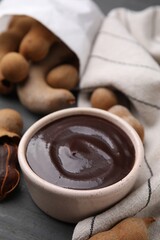 Bowl of tamarind sauce and fresh pods on table