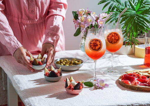 aperol spritz cocktail, on a pale pink linen tablecloth, shadows, sunlight, summer drink in glass