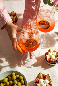 aperol spritz cocktail, on a pale pink linen tablecloth, shadows, sunlight, summer drink in glass