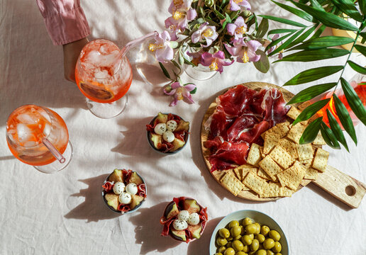 aperol spritz cocktail, on a pale pink linen tablecloth, shadows, sunlight, summer drink in glass