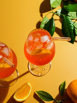 alcohol, aperol spritz cocktail with ice, a misted refreshing drink, on an orange background, sunlight, shadows, a summer drink in a wine glass, drink