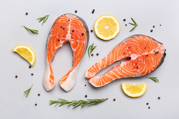 Raw salmon steaks and different spices on grey background