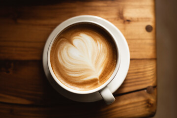 Coffee in white cup on wooden table, with spoon.