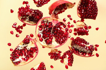 Flying fresh pomegranates with seeds on yellow background