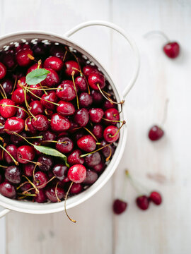 Fresh cherries in white colander.