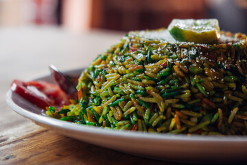 Pilaf biryani is a popular dish in Asian countries. Biryani of colored rice with lime on a white plate on the table