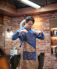 Fototapeta 데님셔츠 위에 앞치마를 입고 영업준비를 하는 바버샵 원장 obraz