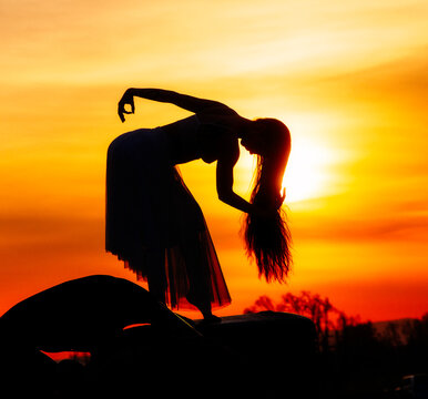 Silhouette of woman with long hair, sun background