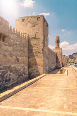 Old city walls with Minaret of Al-Hakim Mosque in Islamic Cairo, Egypt