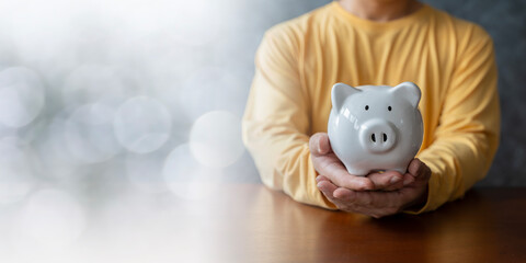 Man hand holding piggy bank on wood table, saving money wealth and financial concept, Business,...