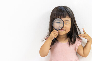 虫眼鏡を持つ笑顔の女の子（日本人、3歳）