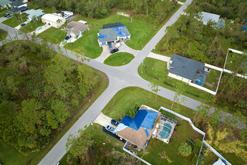 Aerial view of damaged in hurricane Ian house roof covered with blue protective tarp against rain water leaking until replacement of asphalt shingles