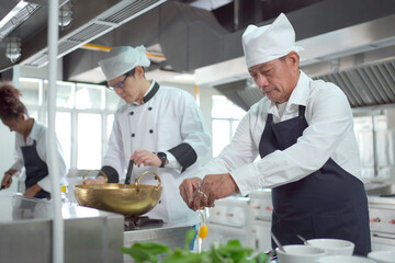 Happy Asian professional chef cooking in kitchen in Asian restaurant. Males professional chef...