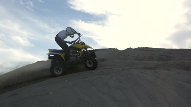 ATV four wheeler rider does wide berm and kicks up sand - slow motion