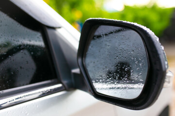 Rain drops on the rearview mirror of a white car after rain.