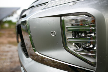 Closeup of the headlight of a modern car in the countryside