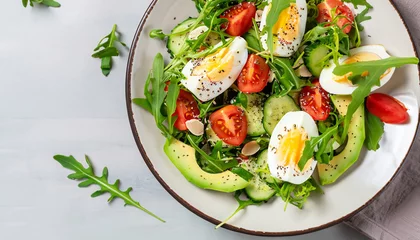  Tasty and healthy salad made of avocado, eggs, tomato, cucumber, cheese, arugula and chia seeds on a light plate. Top view. Flat lay. Banner. © Uuganbayar