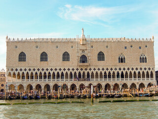 Fototapeta premium Historic Doge's Palace exterior with gondolas by sea is famous Venetian architecture with sunny sky in Venice in Italy