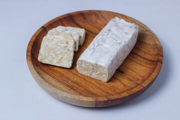 Sliced ​​Raw Tempeh on a wooden cutting board. Vegetable protein.