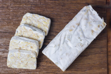Sliced ​​Raw Tempeh on a wooden cutting board. Vegetable protein.