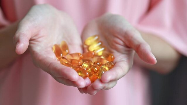 A handful of omega 3 capsules in two female hands. dietary supplement